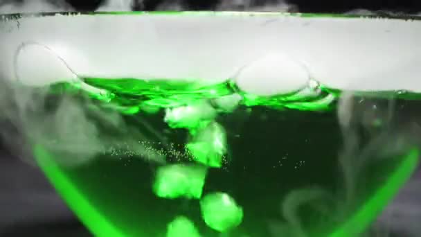 Bubbles of gas in boiling green liquid on a black background. — Stockvideo