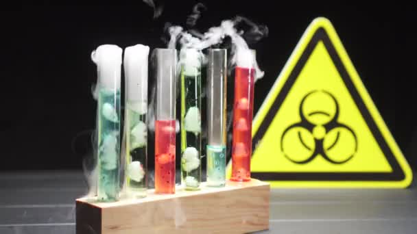 Glas-Reagenzgläser mit kochender Flüssigkeit in verschiedenen Farben vor dem Hintergrund des Biohazard-Zeichens. — Stockvideo