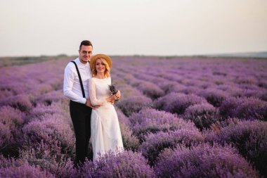 Mutlu yeni evliler günbatımında çiçek açan lavanta tarlasında duruyor.