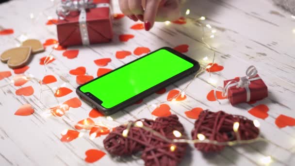 Le mani femminili da vicino usano uno smartphone su una scrivania decorata con cuori . — Video Stock