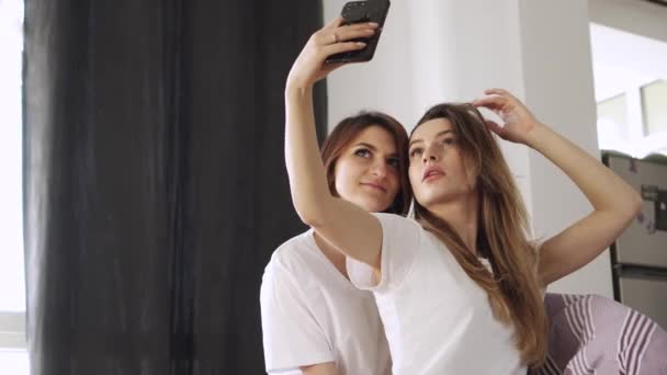 Twee jonge vriendinnen nemen een selfie thuis. — Stockvideo