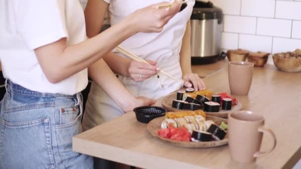 Dos divertido jóvenes lesbianas comer sushi rolls en casa . — Vídeos de Stock