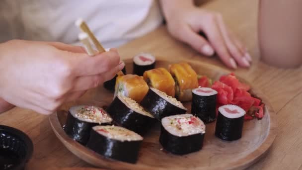 Duas jovens lésbicas engraçadas comem rolos de sushi em casa . — Vídeo de Stock