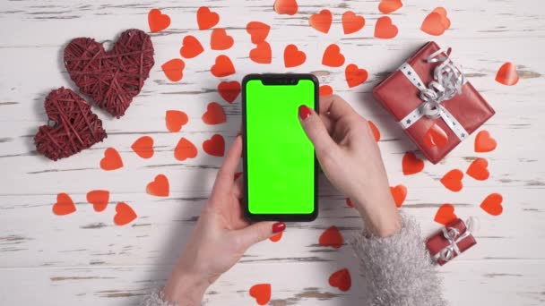 Las manos femeninas de vista superior usan un teléfono inteligente en un escritorio decorado con corazones . — Vídeos de Stock