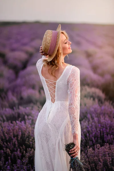 白いドレスの若い女性は日没時にラベンダー畑を歩く — ストック写真