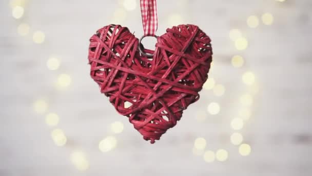 Coeur en osier rouge tourne sur un fond blanc avec bokeh chaud .