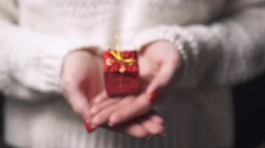 Elinde hediye olan bir kutunun olduğu bir kadının ellerine yakın çekim..