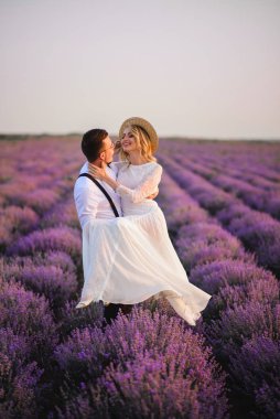 Gün batımında çiçek açan Lavanta Tarlası içinde kollarına gelinini tutan mutlu damat