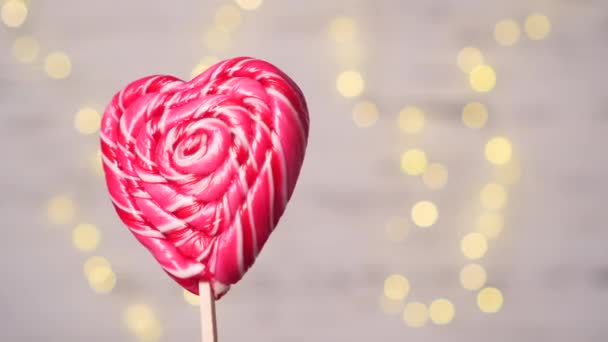 Heart shaped lollipop on blurry lights background. — Stock Video