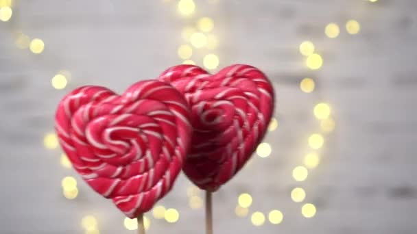 Due caramelle a forma di cuore si muovono sullo sfondo delle luci. — Video Stock