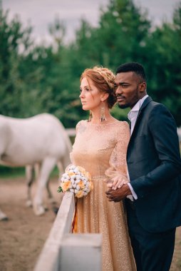 Şehvetli yeni evliler atlarla çevrili çiftlikte duruyorlar