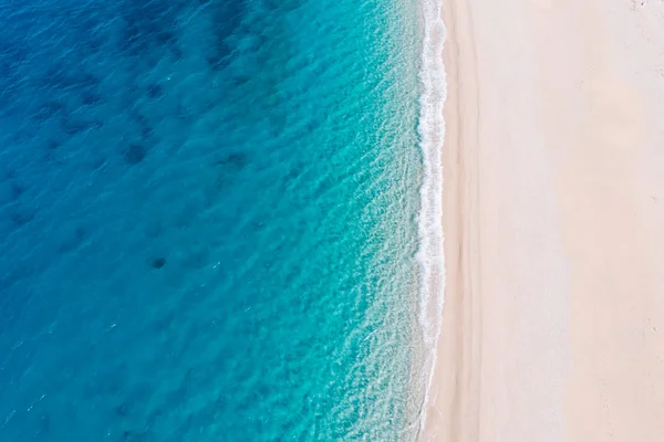 Vista aérea de arriba hacia abajo de una playa de arena blanca a orillas de un hermoso mar turquesa . — Foto de Stock