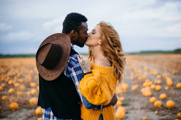 Una joven pareja se besa en un campo de calabazas, de cerca . —  Fotos de Stock