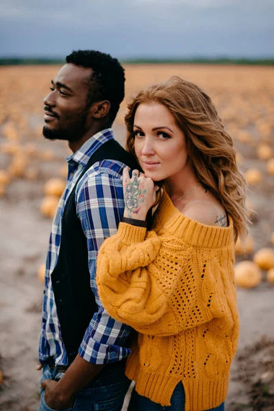 Una pareja romántica está de pie en un campo de calabazas, de cerca . —  Fotos de Stock