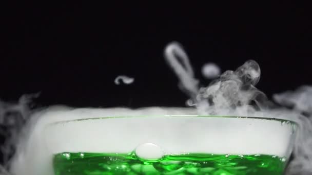 Potion magique est brassée dans un bol en verre sur un fond noir.