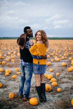 Balkabağı tarlasında duran genç bir çift çiftçi.