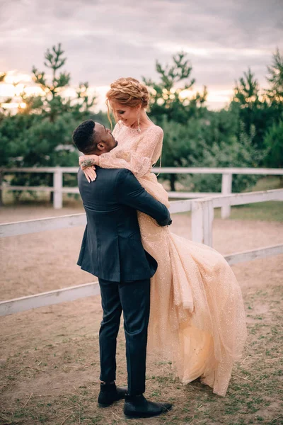 Young bridegroom holds his beautiful bride at the ranch