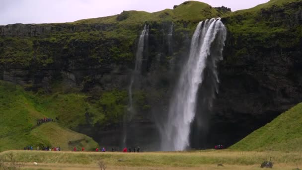 Şelalenin yanında yağmurluk giyen turistler. — Stok video