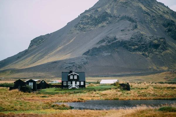 Paisagem islandesa com uma casa contra altas montanhas . — Fotografia de Stock