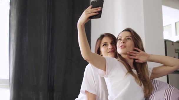 Duas jovens namoradas tiram uma selfie em casa . — Vídeo de Stock