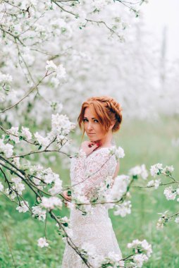 Portrait of a red-haired woman in white blossom.