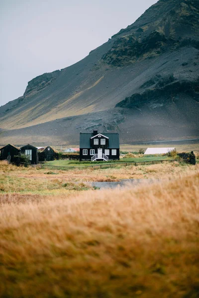 Isländische Herbstlandschaft mit einem Haus gegen hohe Berge. — Stockfoto