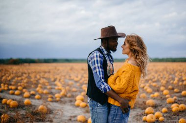 Balkabağı tarlasında duran genç bir çift çiftçi.
