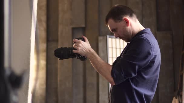 Een jonge mannelijke fotograaf fotografeert een model in de studio. — Stockvideo