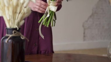 Woman florist puts a finished bouquet on the table.