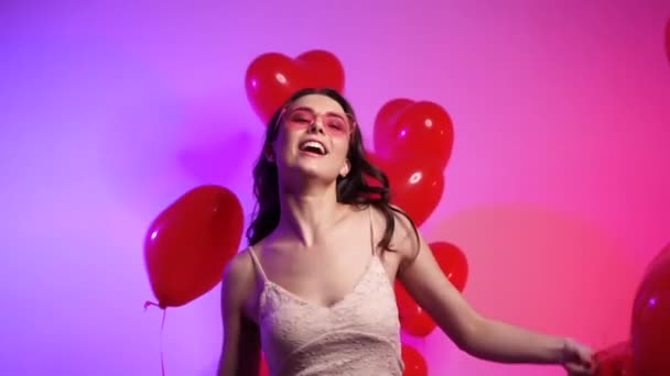 Mulher alegre com bolas em forma de coração dançando. — Vídeo de Stock