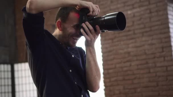 Ένας νεαρός άνδρας φωτογράφος φωτογραφίζει ένα μοντέλο στο στούντιο.. — Αρχείο Βίντεο