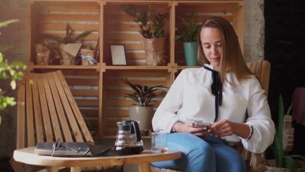 Bir kadın kahve dükkanında akıllı telefon kullanıyor.. — Stok video