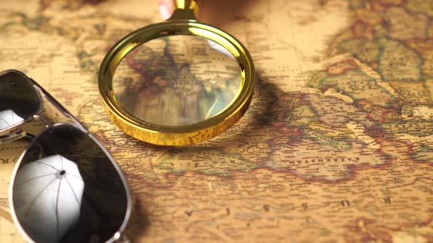 Examining the map with a magnifying glass, close up. — Stockvideo