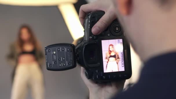 Pantalla de la cámara en manos del fotógrafo durante una sesión de fotos . — Vídeos de Stock