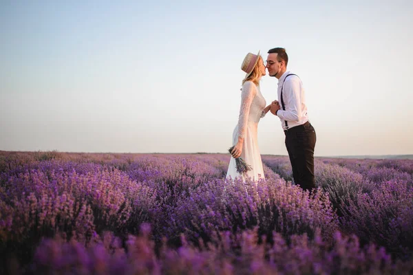 Jeune couple debout au milieu du champ de lavande en fleurs au lever du soleil — Photo