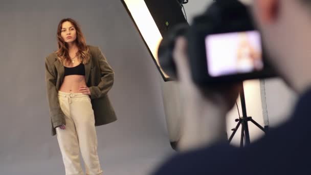 Una modelo femenina posa para un fotógrafo masculino. — Vídeo de stock