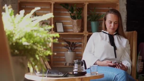 Женщина использует смартфон в кофейне . — стоковое видео