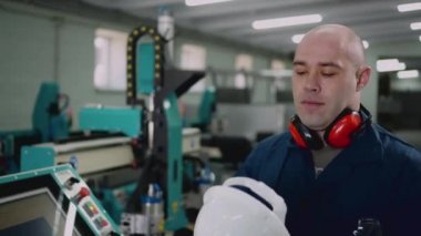 Erkek bir fabrika işçisi kaskını takıyor..