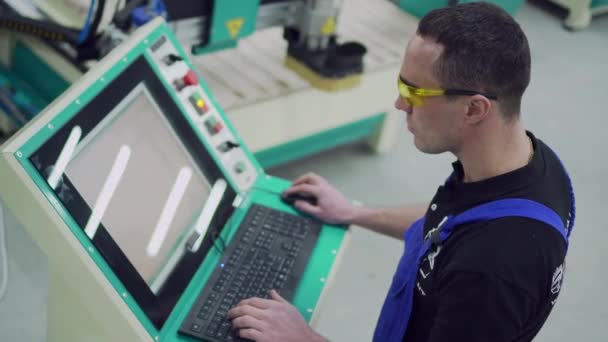 En manlig CNC-maskinoperatör skriver på kontrollpanelen. — Stockvideo