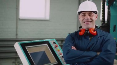 Gülümseyen erkek fabrika işçisi kameraya bakıyor..