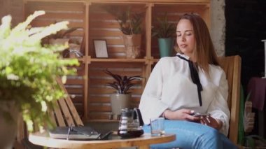 Bir kadın kahve dükkanında akıllı telefon kullanıyor..