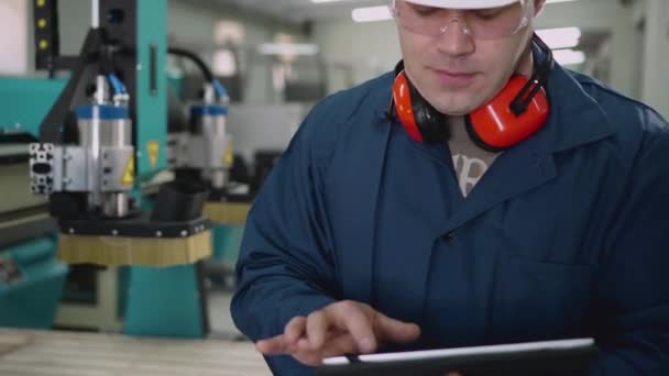 A male factory worker uses a tablet in the workshop. — Stock video