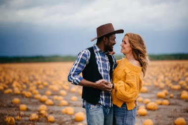 Balkabağı tarlasında duran genç bir çift çiftçi.