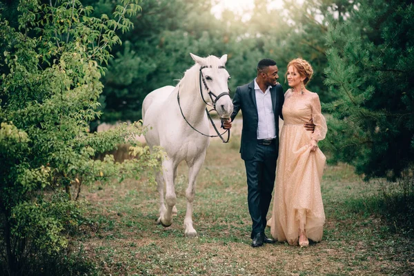 Joyeux couple marchant ensemble sur un ranch avec des chevaux — Photo