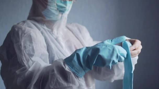 Médecin en combinaison de protection met des gants . — Video