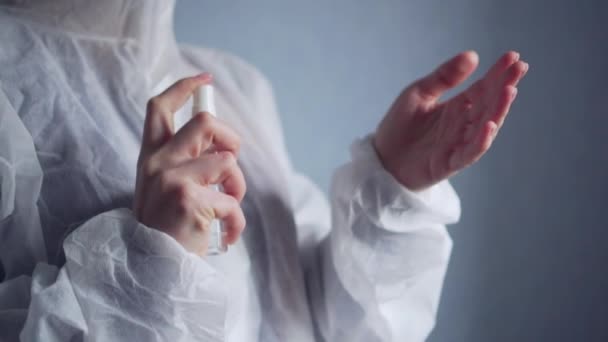 A female medic disinfects her hands with an antiseptic spray. — Stock Video