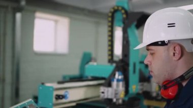 CNC makinesinin operatörü kameraya bakıyor, yakın plan..