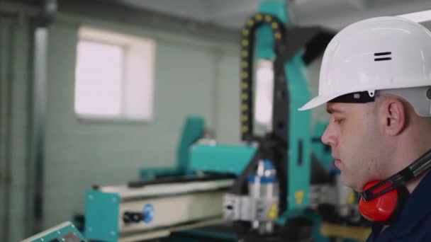 De operator van de CNC machine kijkt naar de camera, close-up. — Stockvideo