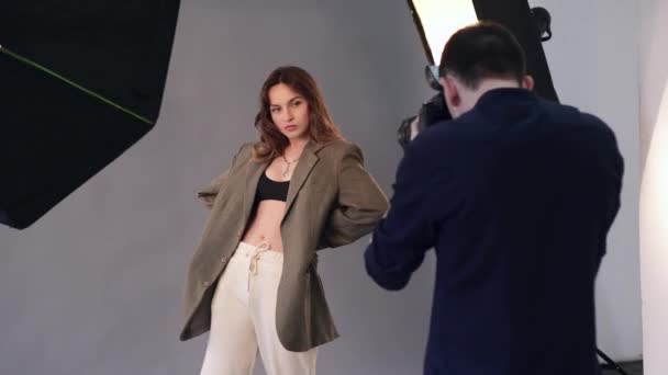 Una modelo femenina posa para un fotógrafo masculino. — Vídeos de Stock