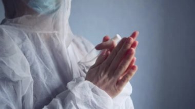 Kadın bir doktor ellerini antiseptik spreyle dezenfekte ediyor..